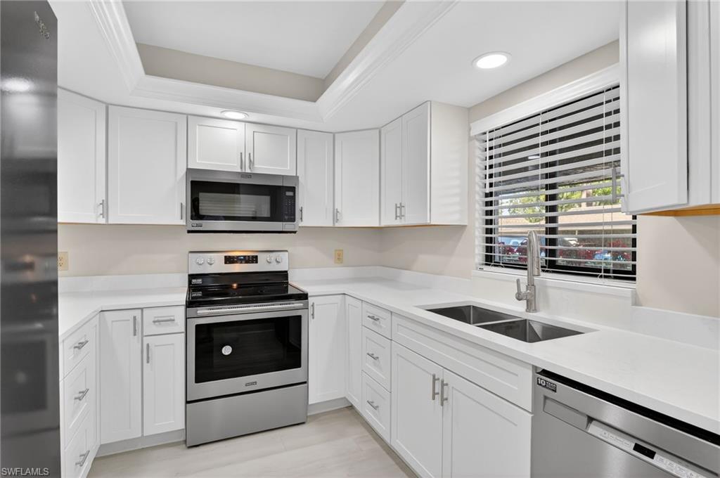 5773 Gage Lane, Unit B101 Naples, FL 34113 - Photo 1 of 39 a kitchen with stainless steel appliances a stove microwave and sink