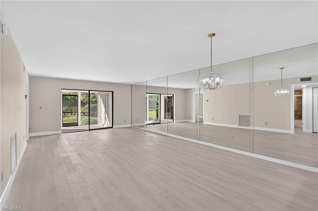 5773 Gage Lane, Unit B101 Naples, FL 34113 - Photo 5 of 39 a view of an empty room with wooden floor and a window