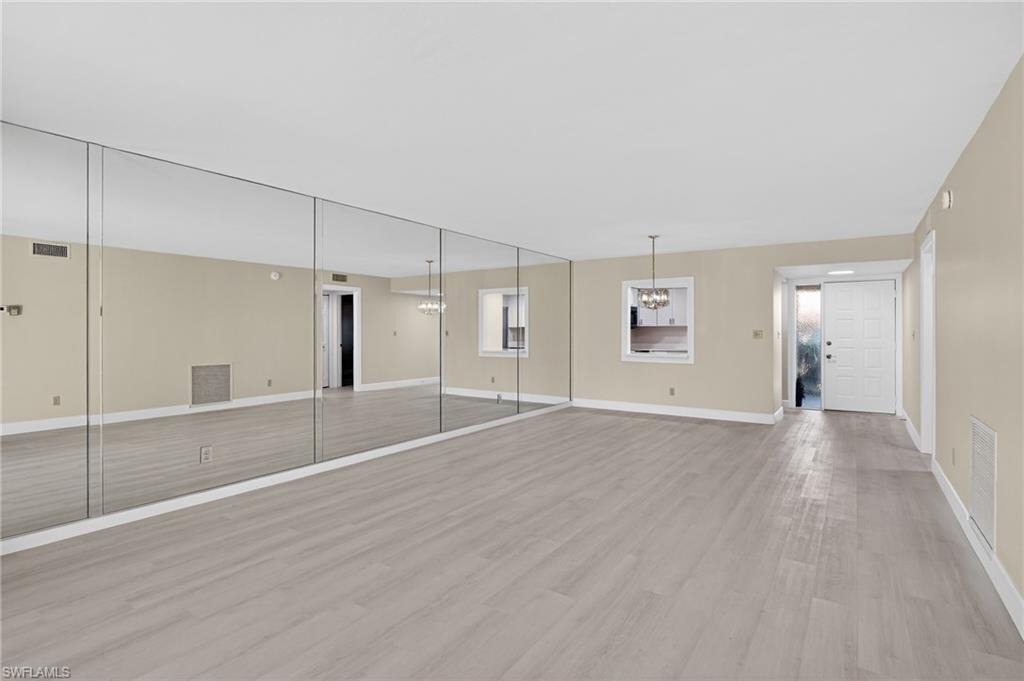 5773 Gage Lane, Unit B101 Naples, FL 34113 - Photo 7 of 39 a view of a big room with wooden floor and windows