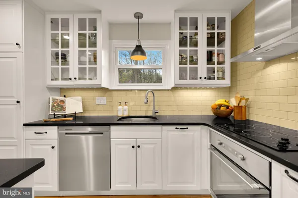 a kitchen with stainless steel appliances granite countertop white cabinets and window