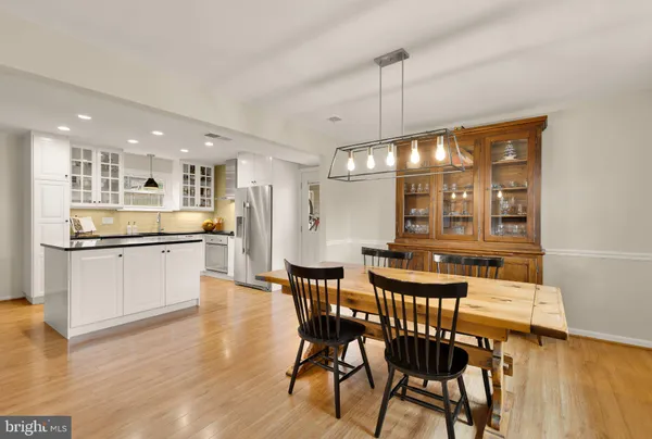 a kitchen with stainless steel appliances kitchen island granite countertop a table chairs sink and cabinets