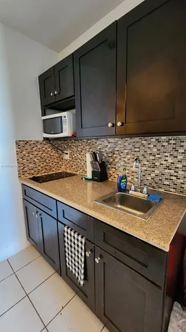 a kitchen with sink a microwave and cabinets