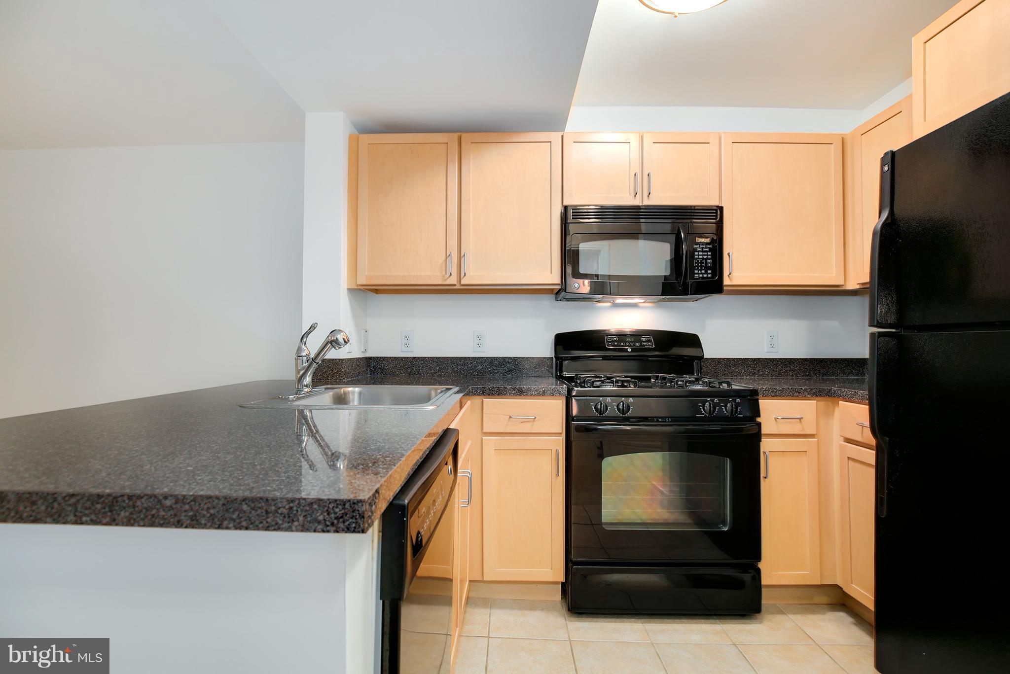 800 4th Street Southwest, Unit S113 Washington, DC 20024 - Photo 5 of 22 a kitchen with granite countertop a stove sink and microwave