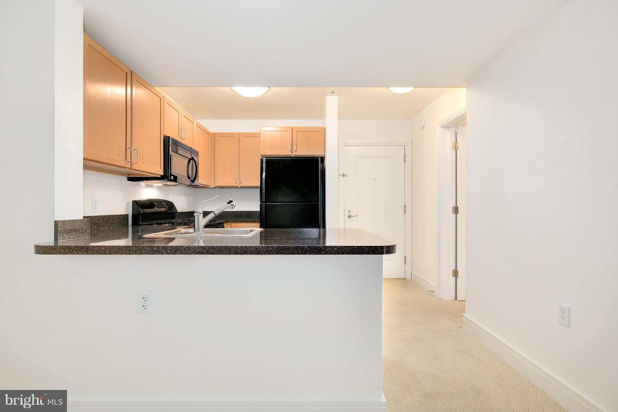 800 4th Street Southwest, Unit S113 Washington, DC 20024 - Photo 8 of 22 a view of a kitchen with kitchen island a sink a counter top space and a refrigerator