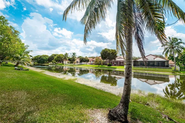 a view of swimming pool with a bench and lawn chairs under an umbrella