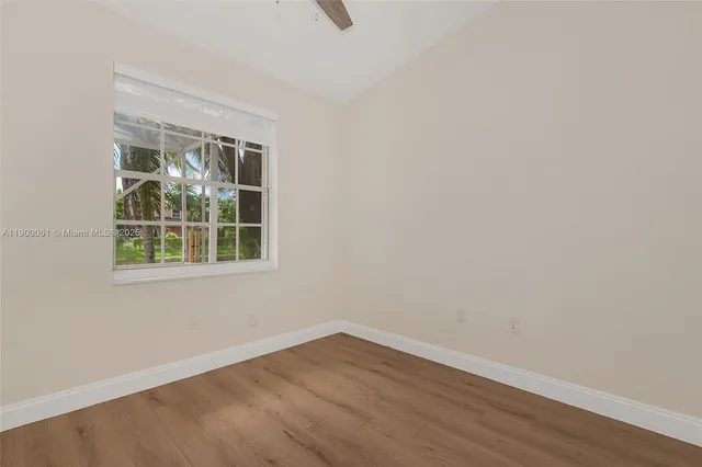 a view of an empty room with wooden floor and closet