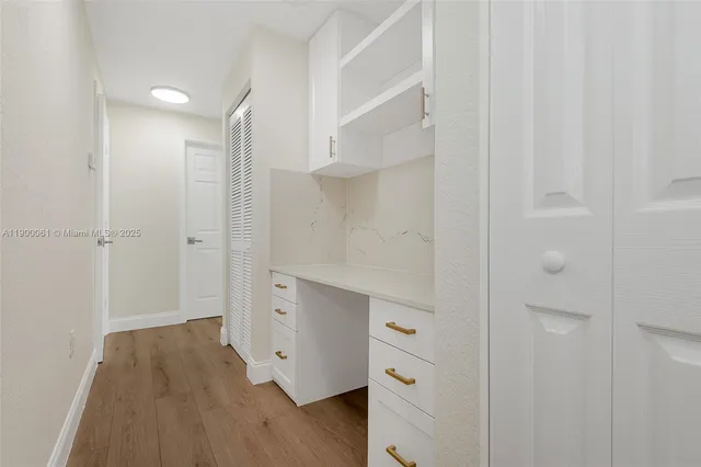an empty room with wooden floor cabinet and windows