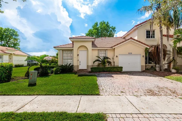 a view of a white house next to a yard with big trees