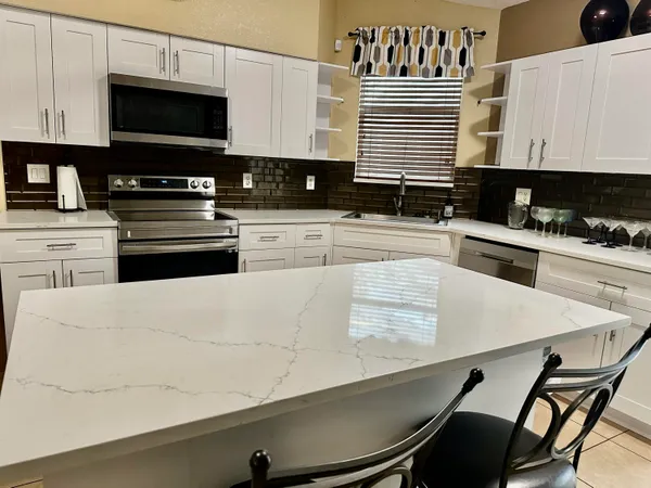 a kitchen with a kitchen island hardwood floor sink stove and white cabinets