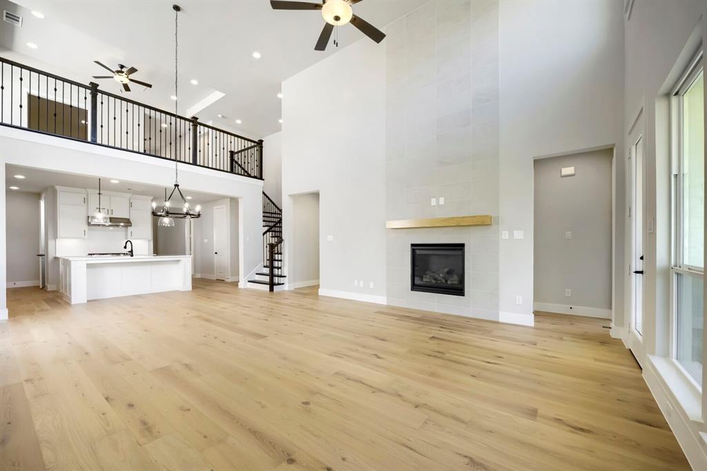 800 Blackberry Road Haslet, TX 76052 - Photo 5 of 28 Spacious living area featuring high ceilings, wood-finish flooring, and a modern fireplace with a light wood mantel