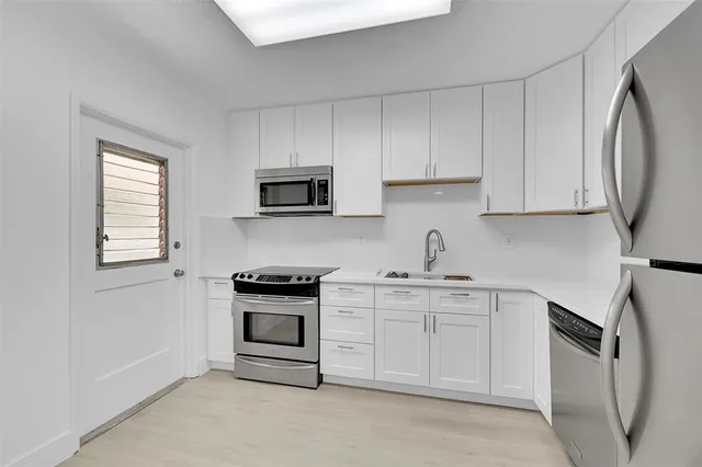 a kitchen with stainless steel appliances granite countertop white cabinets a sink a stove a refrigerator and dishwasher