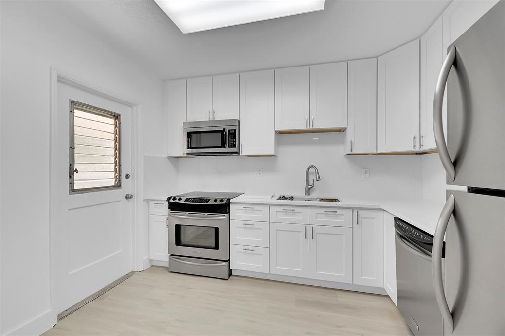 2801 North Palm Aire Drive, Unit 201 Pompano Beach, FL 33069 - Photo 5 of 19 a kitchen with stainless steel appliances granite countertop white cabinets a sink a stove a refrigerator and dishwasher