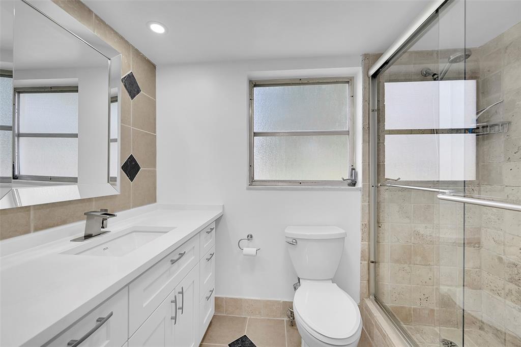 2801 North Palm Aire Drive, Unit 201 Pompano Beach, FL 33069 - Photo 10 of 19 a bathroom with a toilet sink vanity and mirror