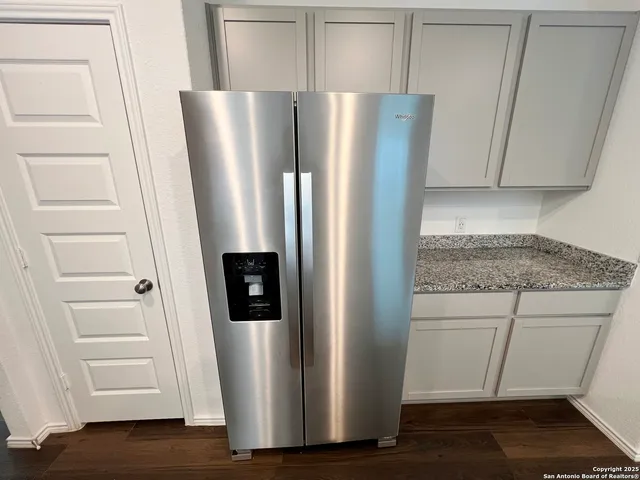 a view of a refrigerator a microwave and cabinets