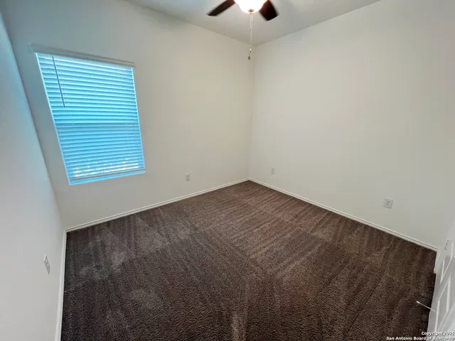 an empty room with a window and a ceiling fan