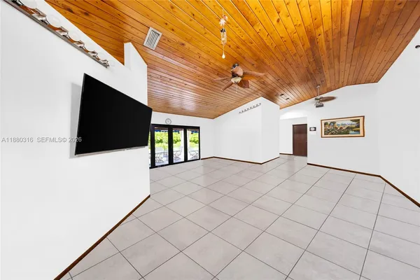 a view of a livingroom with a flat screen tv wooden floor and a ceiling fan