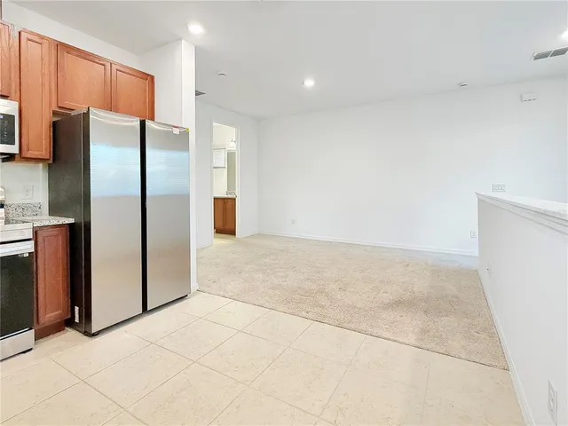 a view of a refrigerator in kitchen and an empty room