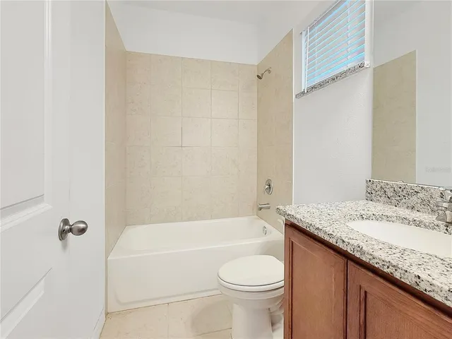 a bathroom with a granite countertop bathtub shower sink vanity and toilet