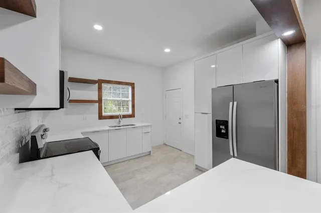 a large white kitchen with a refrigerator a sink dishwasher a stove and a refrigerator with wooden floor