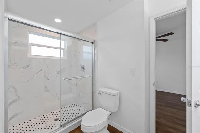 a bathroom with a shower a toilet and a window