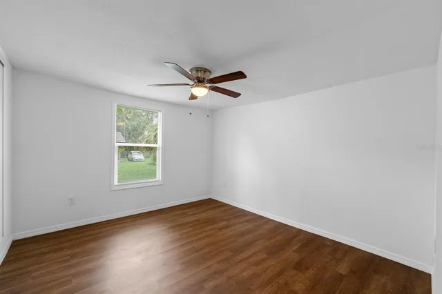 an empty room with a window and ceiling fan