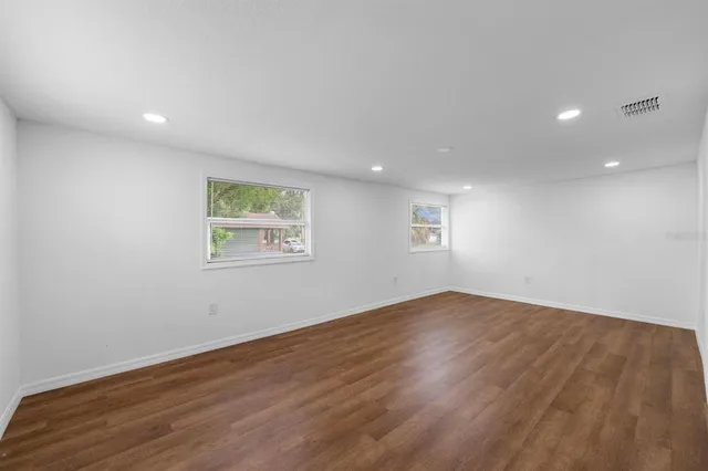 an empty room with wooden floor and windows