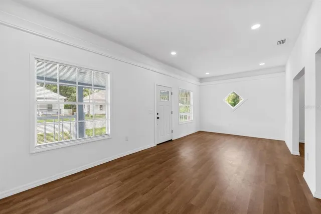 a view of an empty room with wooden floor and a window