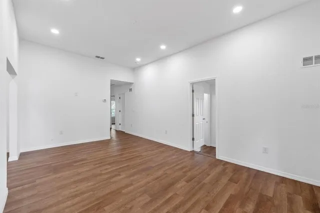 a view of an empty room with wooden floor and window