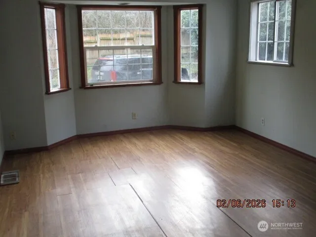 an empty room with wooden floor and windows