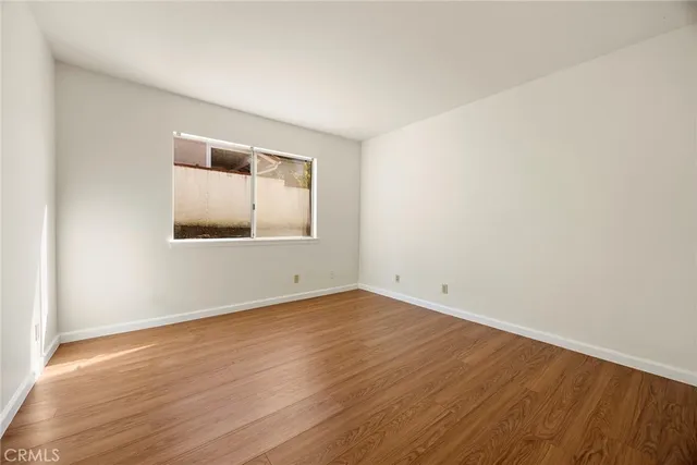 a view of an empty room with wooden floor and closet