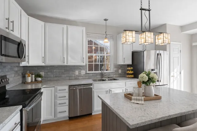 a kitchen with stainless steel appliances granite countertop a sink a stove and a wooden floors