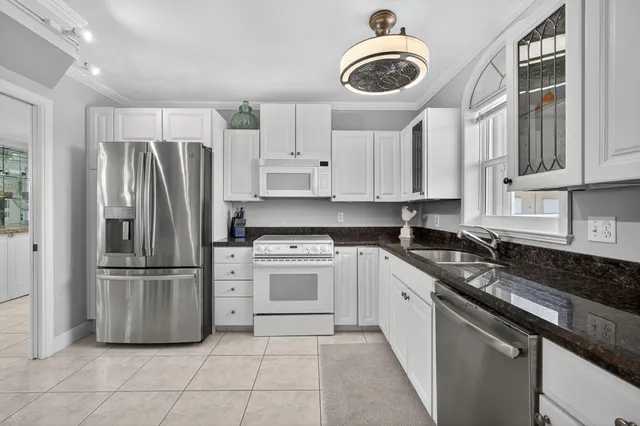 a kitchen with stainless steel appliances granite countertop a refrigerator a stove and a sink