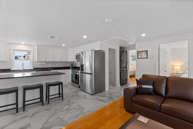 a living room with stainless steel appliances kitchen island granite countertop a couch and a refrigerator