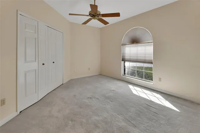 an empty room with windows and fan