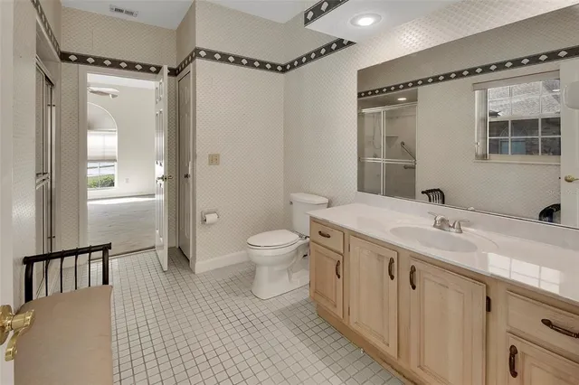 a spacious bathroom with a double vanity sink toilet mirror and a shower