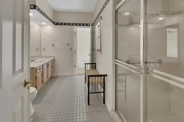 a bathroom with a double vanity sink a toilet a mirror and shower