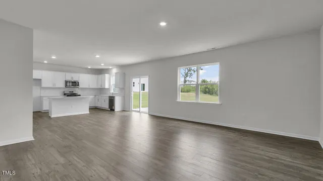 a view of an empty room with window and wooden floor