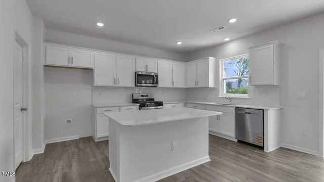 a kitchen with a sink a stove a refrigerator and white cabinets