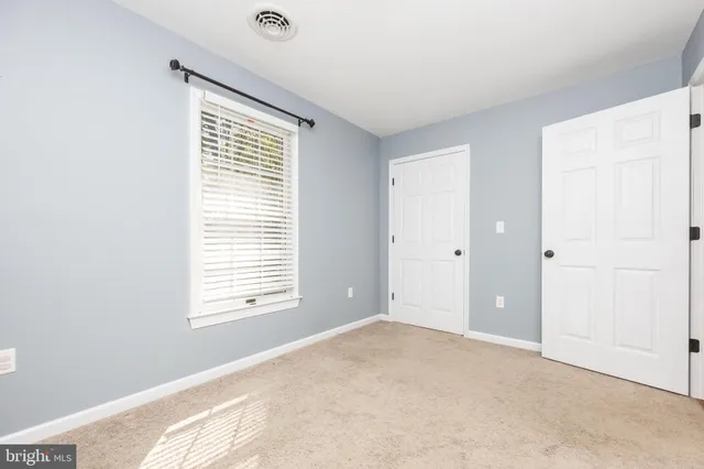 an empty room with chandelier fan and windows