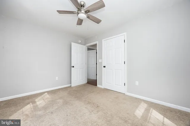 an empty room with ceiling fan and window