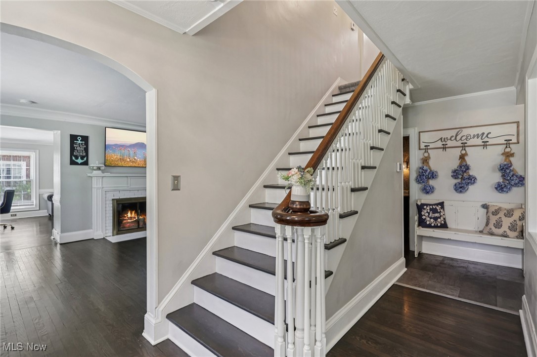 128 Overwood Road Akron, OH 44313 - Photo 2 of 40 Stairs featuring arched walkways, wood finished floors, crown molding, and a fireplace