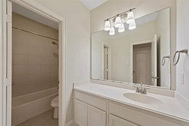 a bathroom with a granite countertop sink a toilet and a mirror