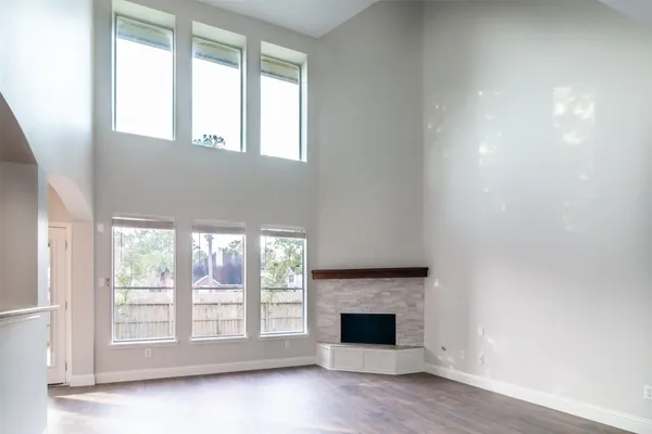 an empty room with wooden floor fireplace and windows
