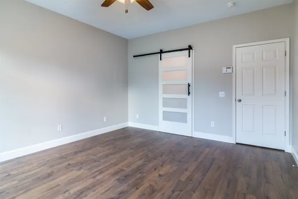 a view of an empty room with wooden floor and closet