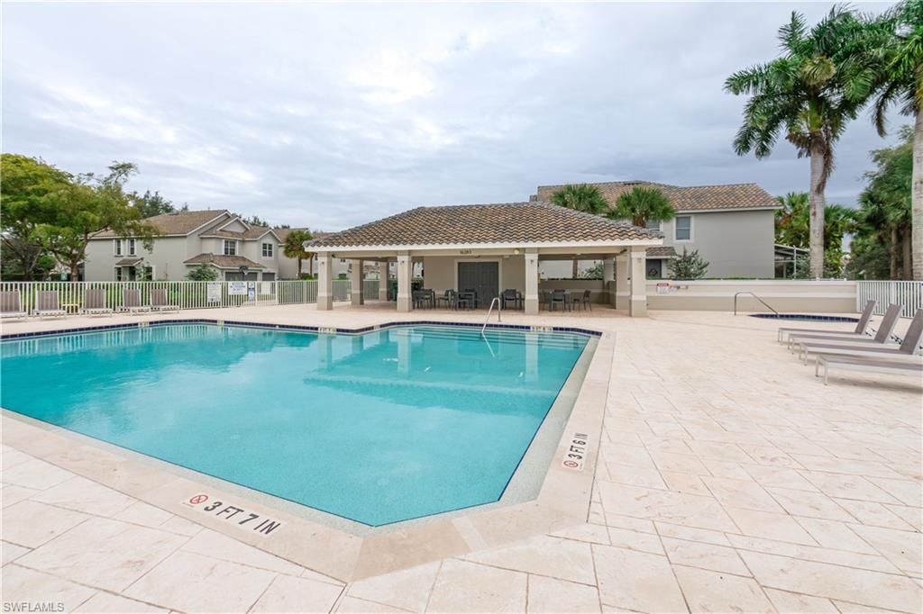 16235 Ravina Way Naples, FL 34110 - Photo 18 of 18 Community swimming pool with a tiled deck, covered patio, and adjacent hot tub, surrounded by mature palm trees