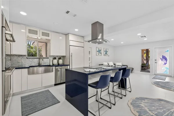 a kitchen with stainless steel appliances kitchen island granite countertop a table chairs sink and cabinets