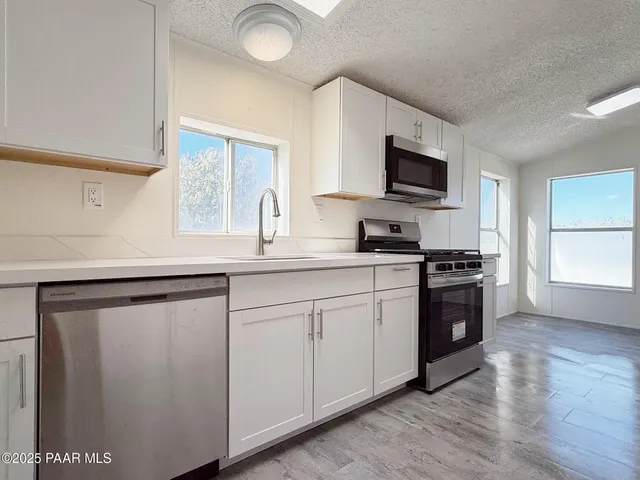 a kitchen with granite countertop a sink cabinets and stainless steel appliances