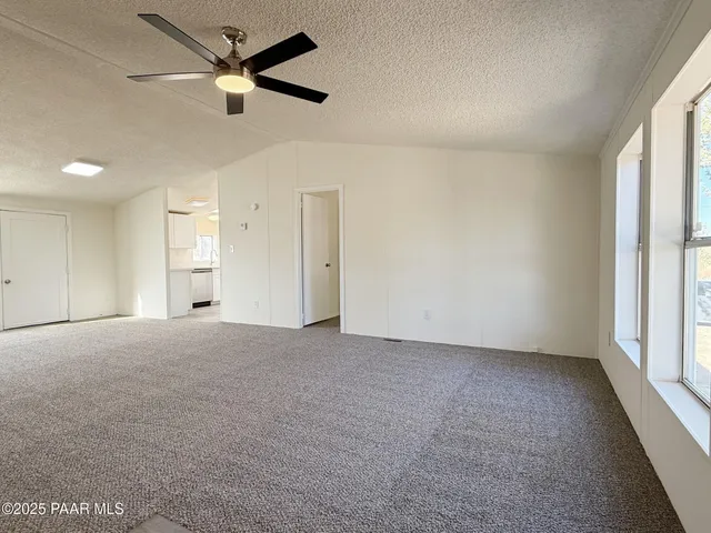 en empty room with windows and ceiling fan