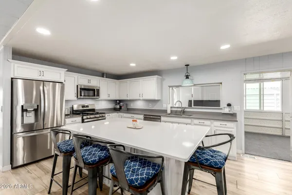 a open kitchen with stainless steel appliances kitchen island a white counter space a sink and a refrigerator
