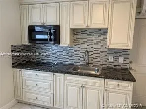 a kitchen with granite countertop white cabinets and stainless steel appliances